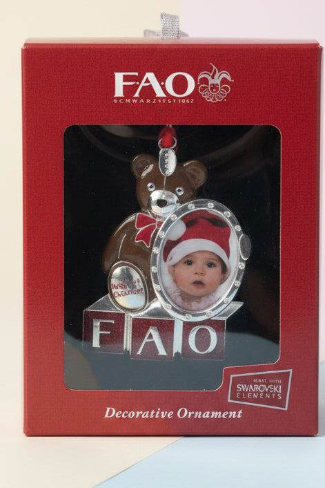 The Flip Side FAO Schwarz baby's first Christmas ornament featuring a teddy bear, photo frame, and Swarovski crystals.