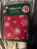 The Flip Side rectangular holiday tablecloth in red with white snowflake patterns, 60 by 104 inches in packaging.