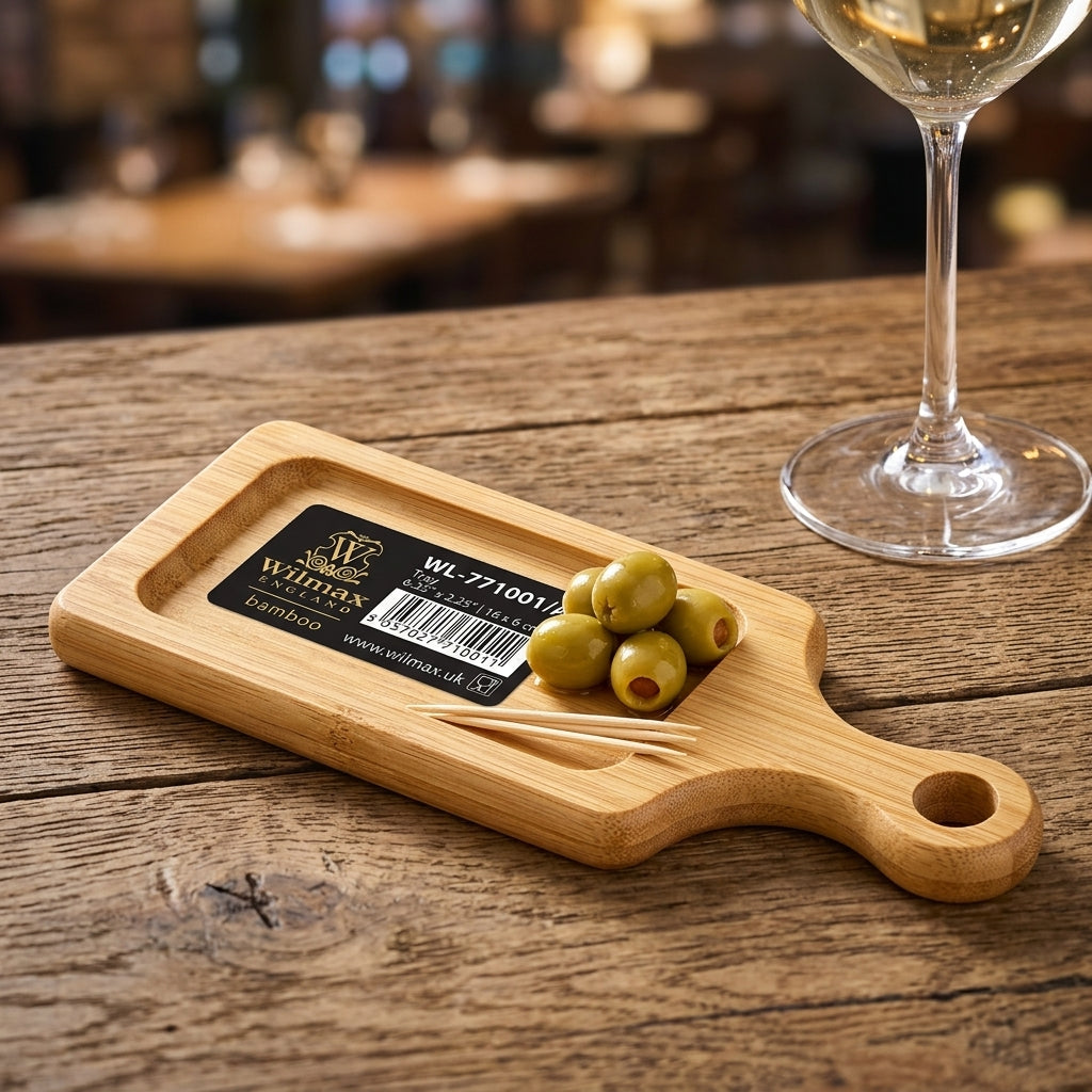 Miniature bamboo serving paddle on dining table with olives and glassware